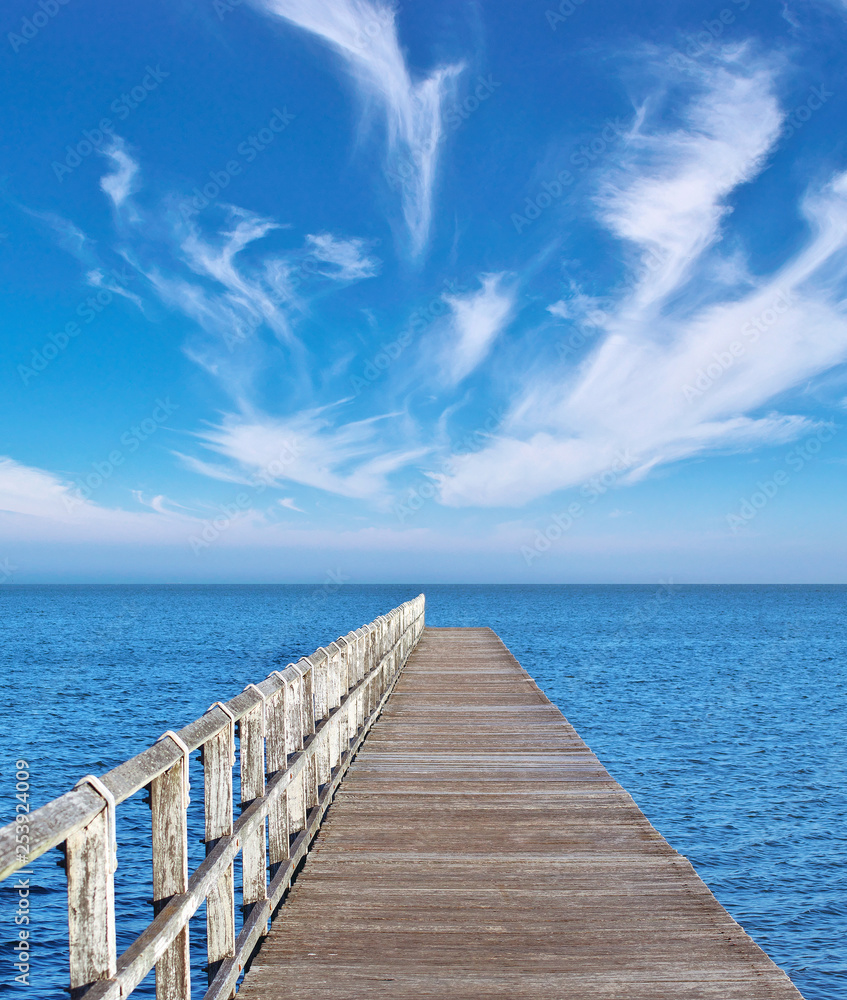 Jetty with blue sky and streaking clouds on the horizon