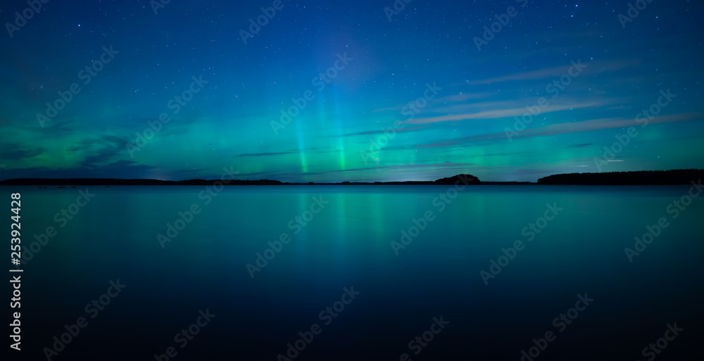 Northern lights dancing over calm lake after the sunset under the blu time