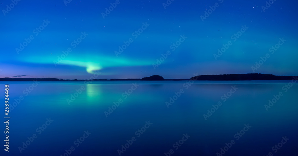 Northern lights dancing over calm lake after the sunset under the blu time Northern lights dancing over calm lake after the sunset under the blu time