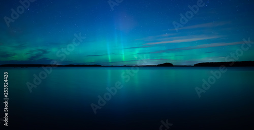 Northern lights dancing over calm lake after the sunset under the blu time © Conny Sjostrom