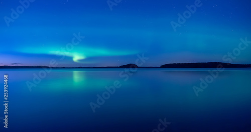 Northern lights dancing over calm lake after the sunset under the blu time © Conny Sjostrom