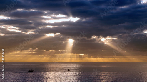 morning sun bursting through dark clouds over the sea