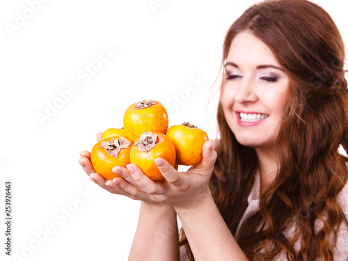 Cheerful woman holds persimmon kaki fruits, isolated