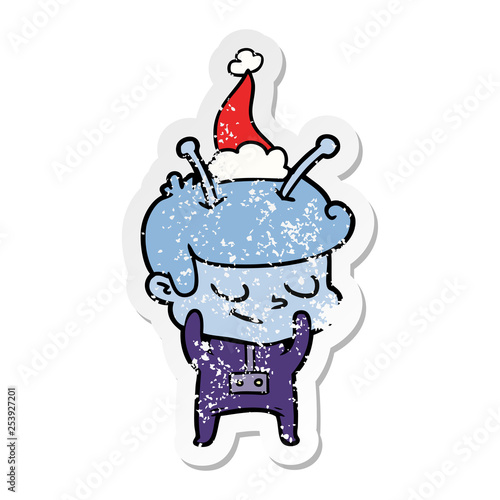 shy distressed sticker cartoon of a spaceman wearing santa hat