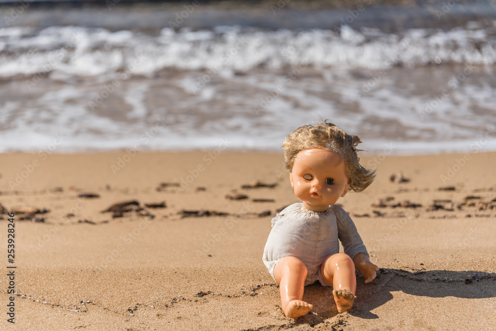 Old Broken Toy Doll Sitting on a Beach in Italy Old Broken Toy Doll Sitting on a Beach in Italy