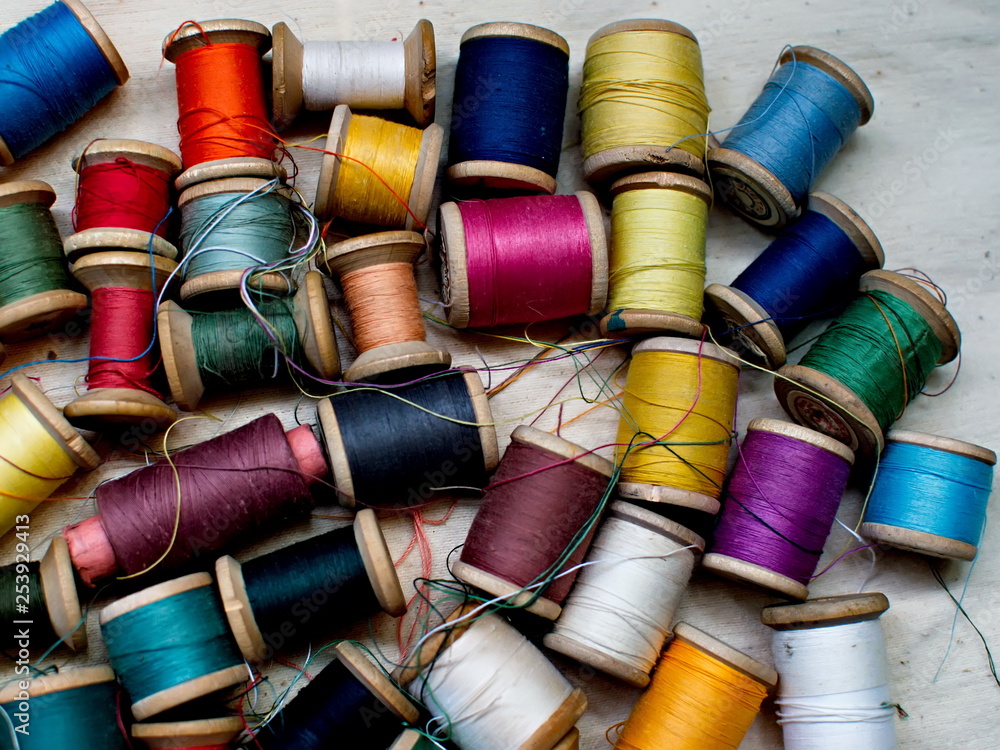 Old multi-colored coils lie in a box. A pile of coils with colored threads. Sewing supplies. Many coils of thread. Old multi-colored coils lie in a box. A pile of coils with colored threads. Sewing supplies. Many coils of thread.