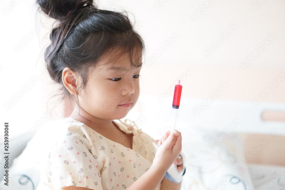 Asian child cute or kid girl Influenza sick holding and eating or taking sweet red drug or water medicine by syringe pump on bed at hospital room for pediatric patient treatment and healthcare Asian child cute or kid girl Influenza sick holding and eating or taking sweet red drug or water medicine by syringe pump on bed at hospital room for pediatric patient treatment and healthcare