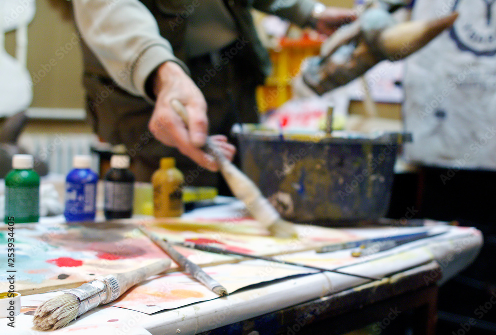 Shallow depth of field on brushes and man painting in the background Shallow depth of field on brushes and man painting in the background