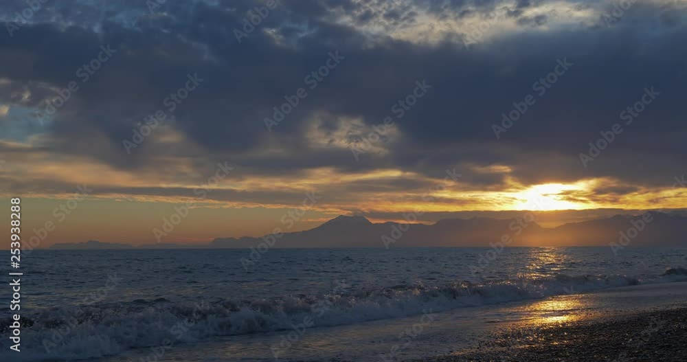 Beautiful sunset at beach with golden sun reflection on the sea and mountain background Beautiful sunset at beach with golden sun reflection on the sea and mountain background