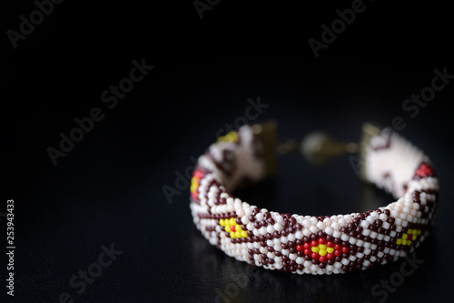 Beige bracelet with oriental pattern on a dark background close up