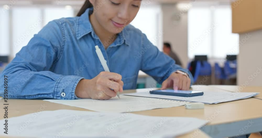 Woman write on the paper with cellphone at home Woman write on the paper with cellphone at home