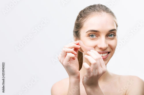 Portrait of smiling woman without make up glues pink patches under her eyes
