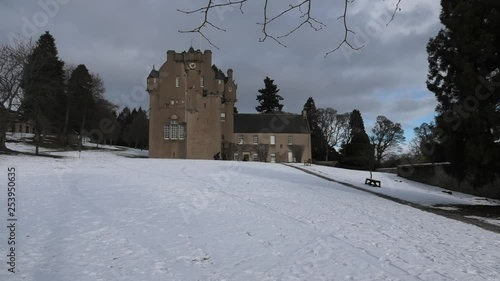 Crathes Castle in snow sunlit with overcast sky photo