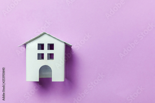 Simply design with miniature white toy house isolated on purple violet pastel colorful trendy background. Mortgage property insurance dream home concept. Flat lay top view copy space