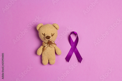 Children's toy with a Purple epilepsy awareness ribbon on a purple background. World epilepsy day.
