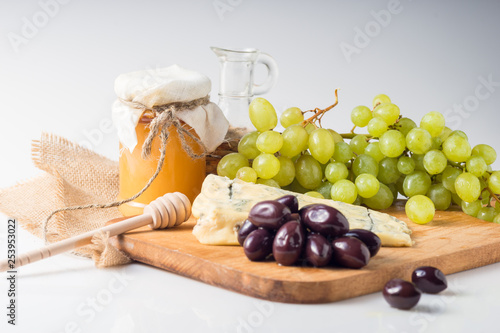 White cheese plate with olives, honey, grapes. Assortment of wine snack, appetizer or gourmet dinner.