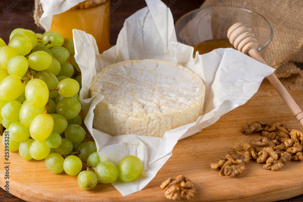 Camembert cheese on a wooden board with honey, fruits and nuts Camembert cheese on a wooden board with honey, fruits and nuts