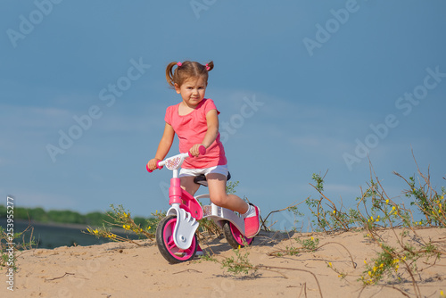 Fototapeta Naklejka Na Ścianę i Meble -  Good luck kids, laughter and joy. Baby sport. New routes. Baby girl riding on pink bicycle in the city park for children. Sportive kid enjoying sunny summer, spring or autumn day outdoors.