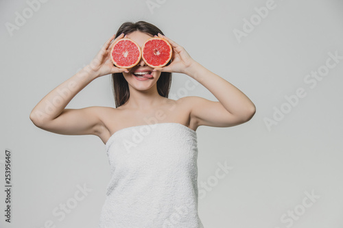 Young sexy girl posing with slices of red grapefruit on her face covering her eyes.