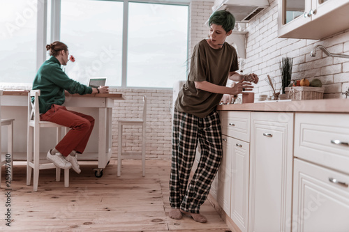 Girlfriend wearing pajamas hiding from man and drinking alcohol photo