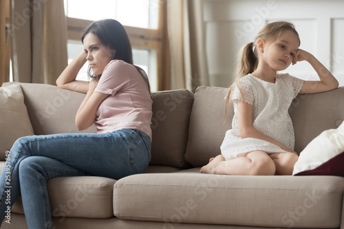 фотографія Stubborn mother and child girl sitting turned away on sofa