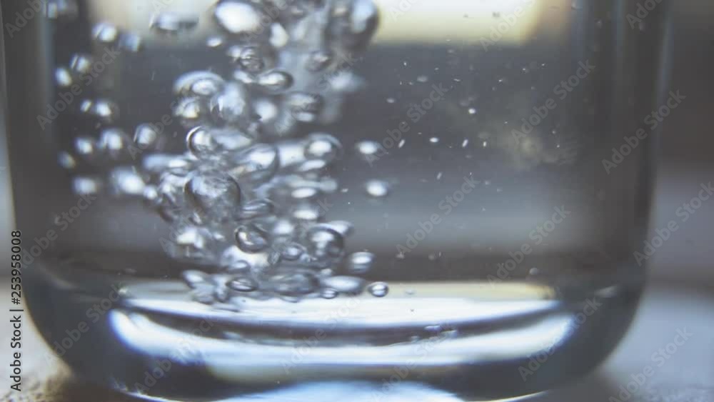 Water bubbles while pouring in glass up close in slow motion Water bubbles while pouring in glass up close in slow motion