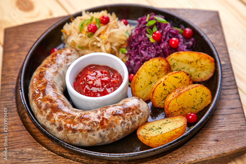 sausage with baked potatoes and salad on the wooden background