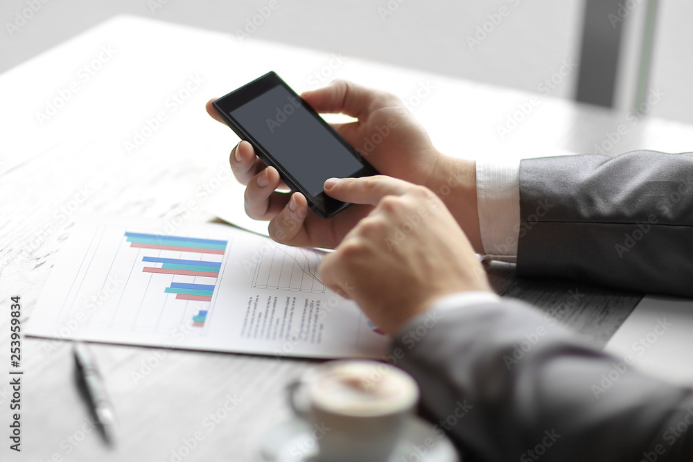 close up.the businessman uses his smartphone to check financial data close up.the businessman uses his smartphone to check financial data