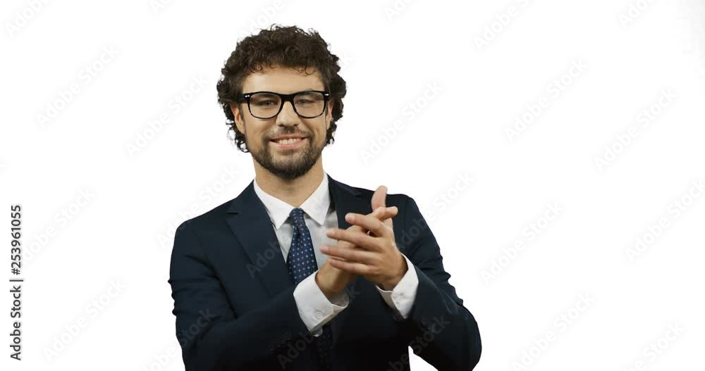 Cheerful Caucasian businessman in the suit, tie and glasses clapping in the hands and laughing on the white back wall. Cheerful Caucasian businessman in the suit, tie and glasses clapping in the hands and laughing on the white back wall.