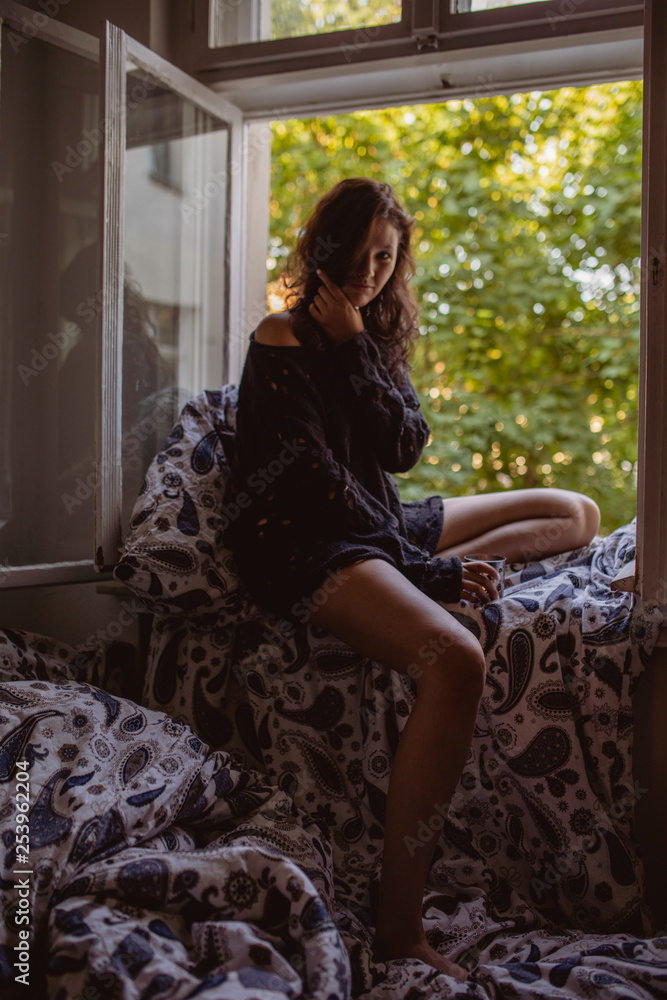Fototapeta premium Junge Frau auf Fensterbrett