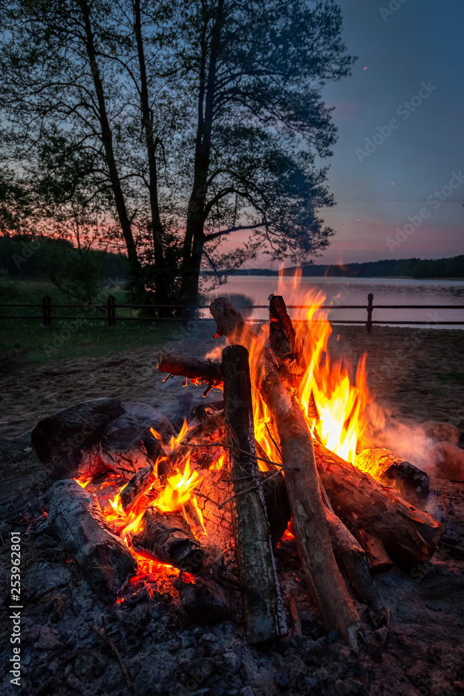 Stunning bonfire at dusk by the lake, summer in Poland Stunning bonfire at dusk by the lake, summer in Poland