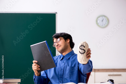 Young male teacher in front of chalkboard 