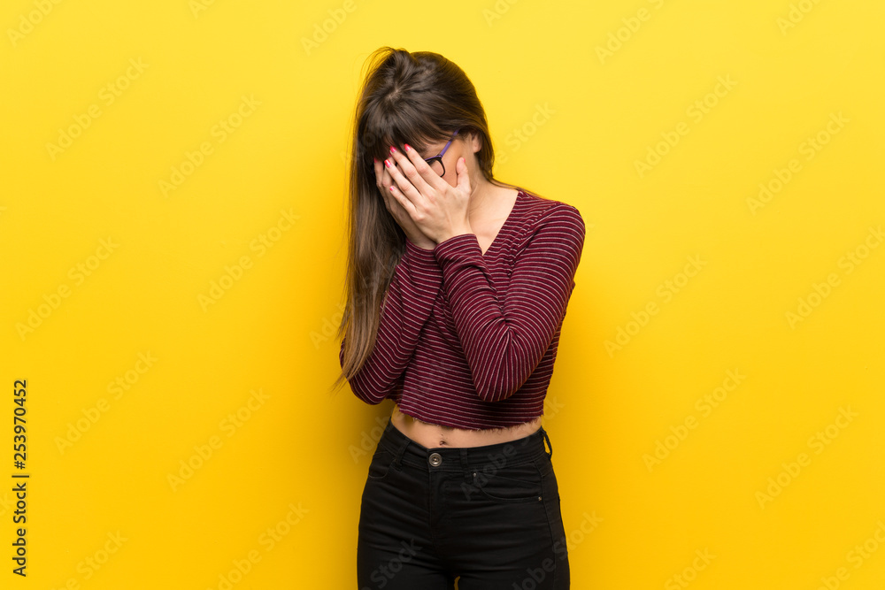 Woman with glasses over yellow wall with tired and sick expression Woman with glasses over yellow wall with tired and sick expression