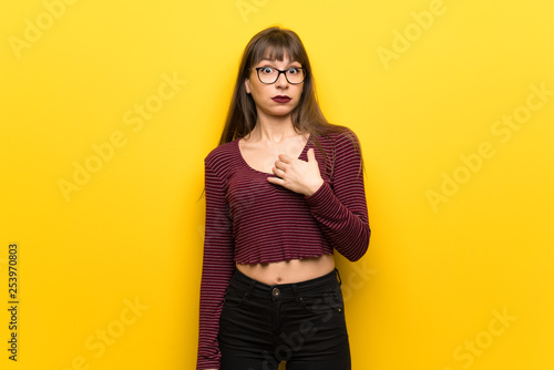 Woman with glasses over yellow wall surprised and shocked while looking right © luismolinero