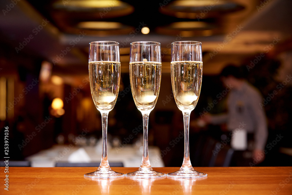 Glasses with champagne on the bar counter in a restaurant against a dark background. Glasses with champagne on the bar counter in a restaurant against a dark background.