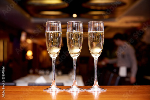 Glasses with champagne on the bar counter in a restaurant against a dark background.