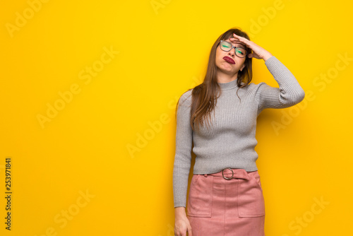 Woman with glasses over yellow wall with surprise and shocked facial expression