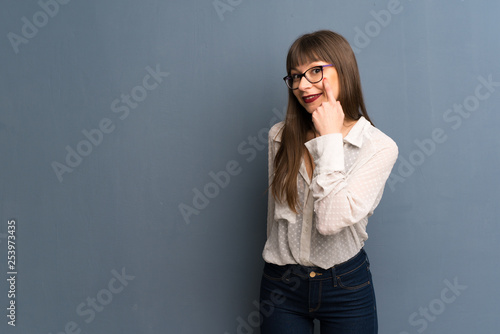 Woman with glasses over blue wall looking to the front