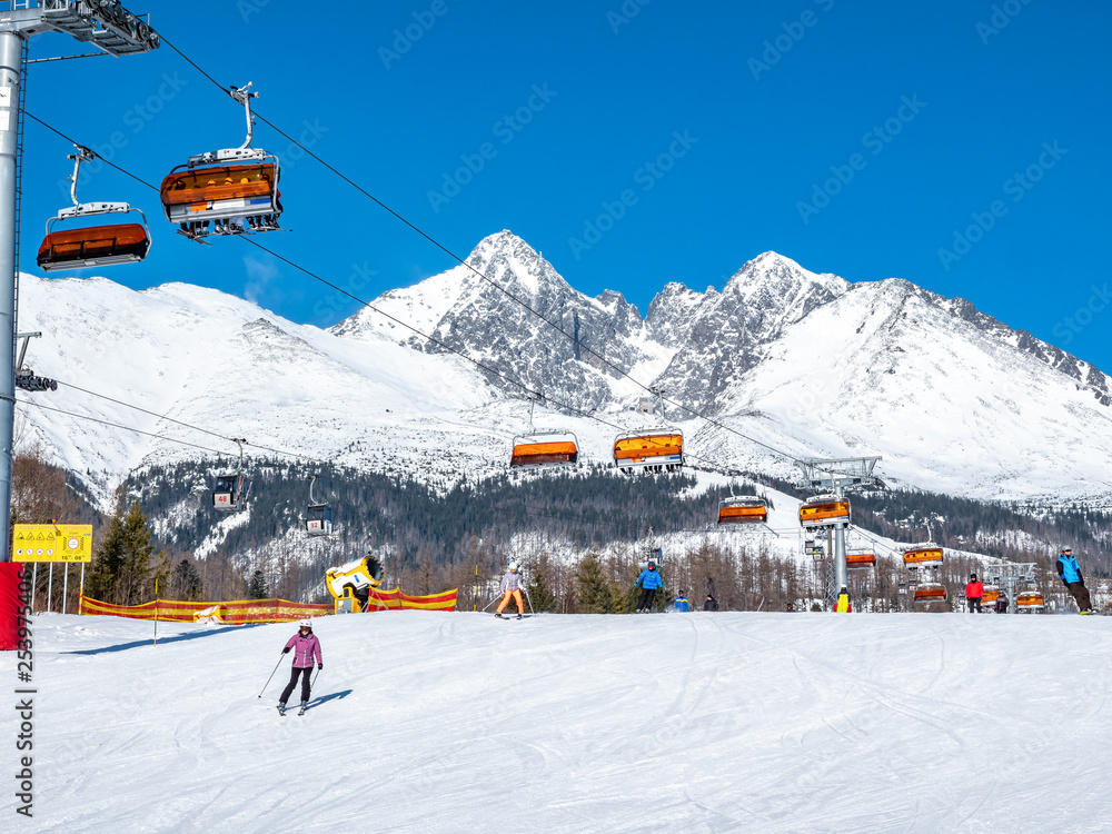 Chair lifter in ski resort with skiers and Tatry mountains in the back ground