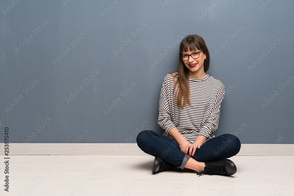 Woman with glasses sitting on the floor laughing looking to the front Woman with glasses sitting on the floor laughing looking to the front