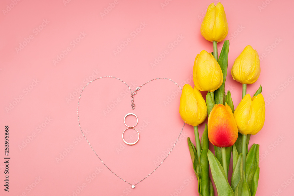 International Womens Day with flowers and heart shape necklace on pink background
