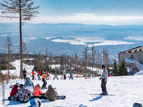 View of the winter ski resort in Tatrzanska Lomnica in Slovakia with colorfull skiers.