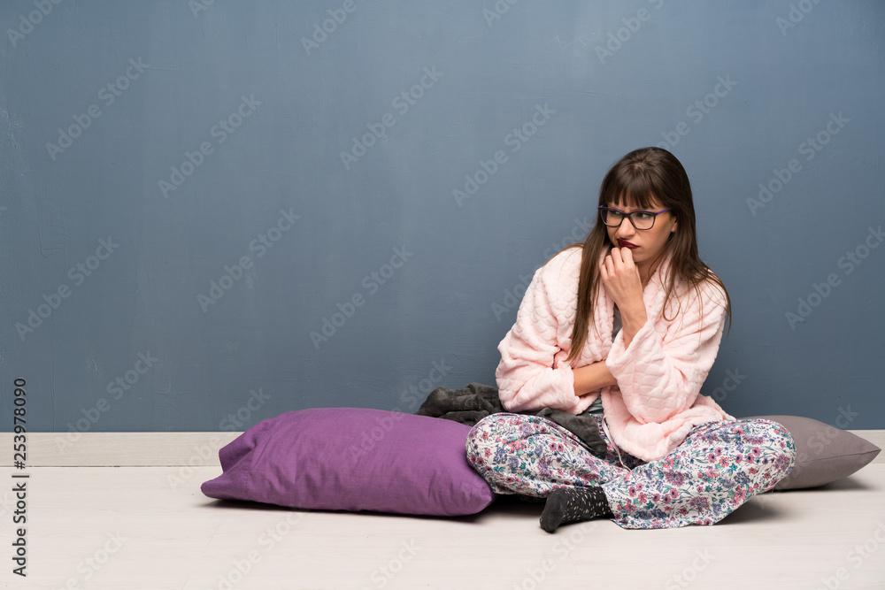 Woman in pajamas on the floor having doubts Woman in pajamas on the floor having doubts