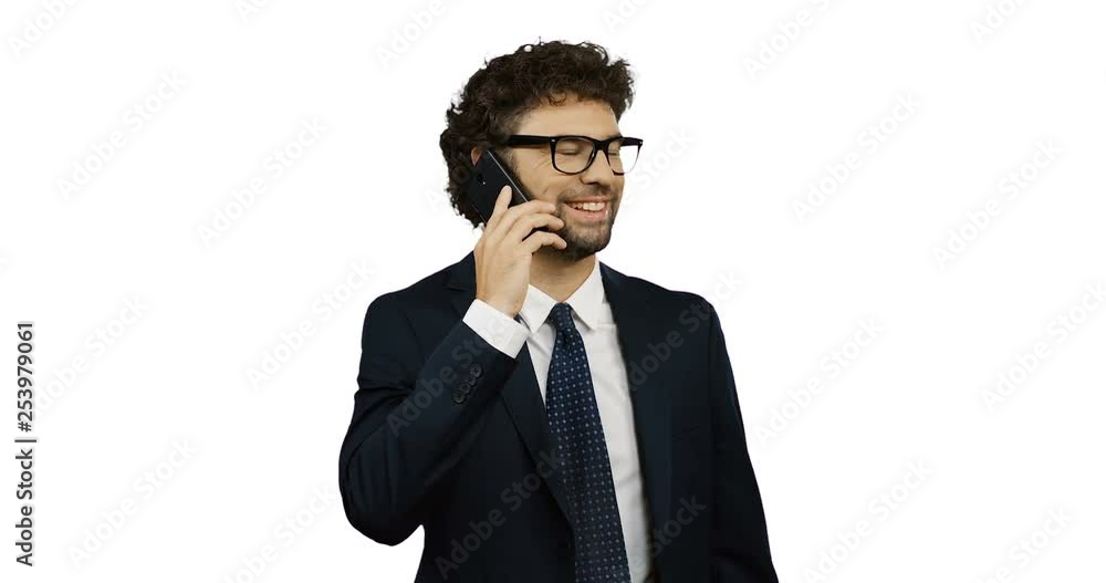 Attractive Caucasian man in the glasses, suit and tie talking on the phone cheerfully on the white wall background. Attractive Caucasian man in the glasses, suit and tie talking on the phone cheerfully on the white wall background.