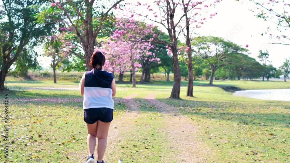 A fat Asian woman walking in natural sunlight in the morning...She is trying to lose weight with exercise.  concept health with exercise.