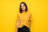 Young woman over yellow wall smiling