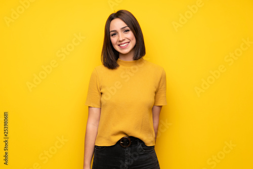 Fotografie, Obraz Young woman over yellow wall smiling