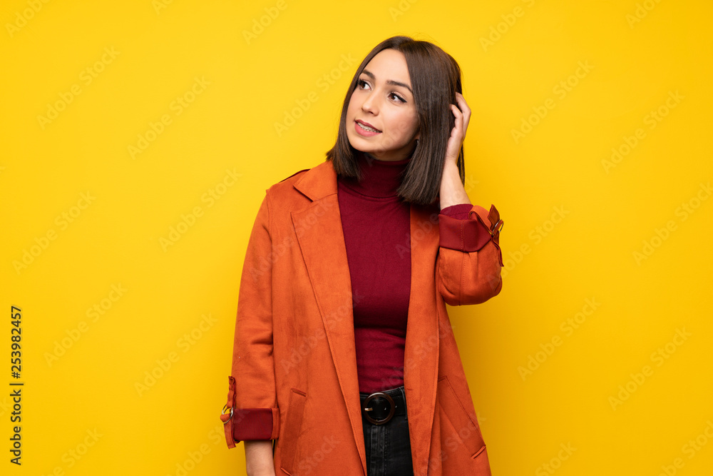 Young woman with coat thinking an idea while scratching head Young woman with coat thinking an idea while scratching head