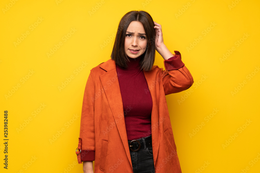 Young woman with coat having doubts while scratching head Young woman with coat having doubts while scratching head