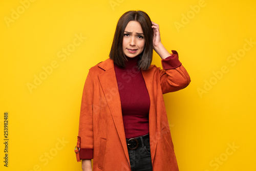 Young woman with coat having doubts while scratching head © luismolinero